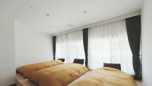 A bedroom with two beds, a window with sheer curtains, and a wooden floor. - kadoya (Kosuge)