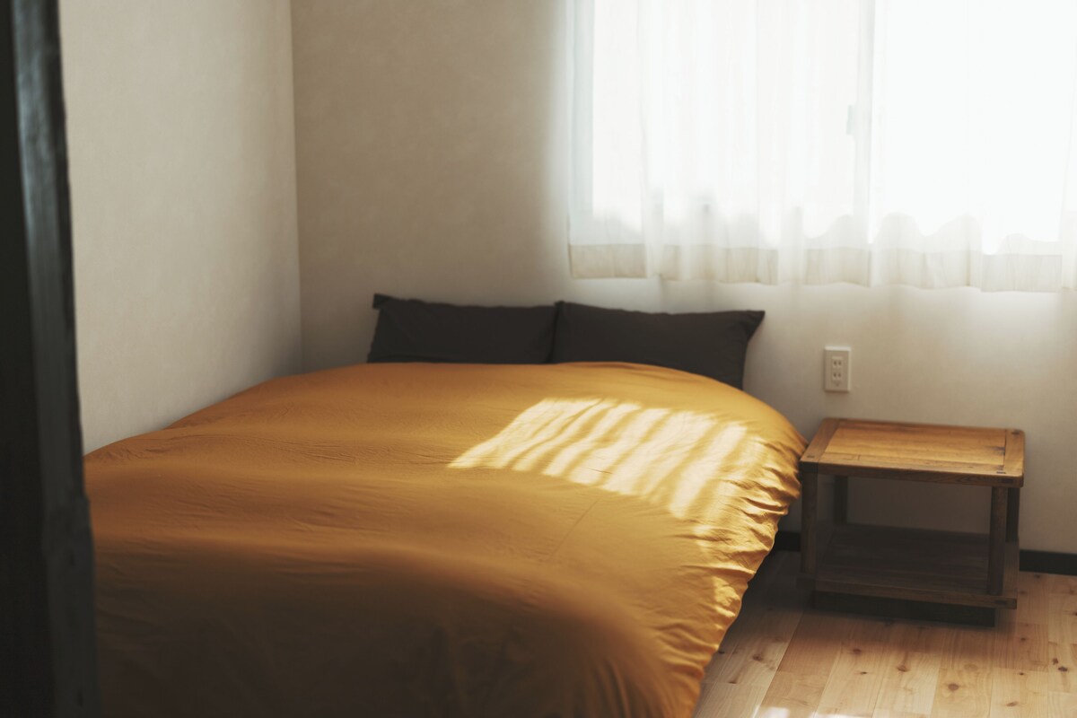 Une chambre à coucher avec un lit, une table de chevet et une fenêtre avec des rideaux.