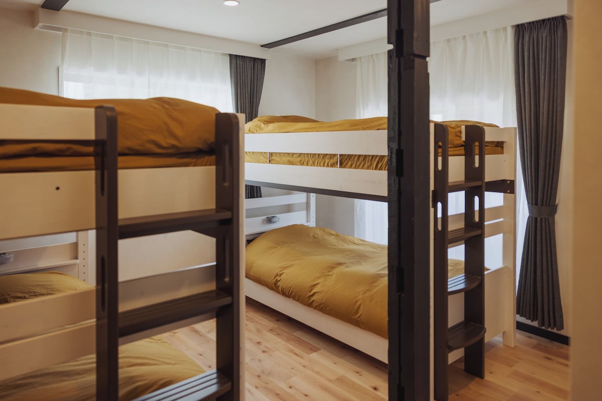 Une chambre avec des lits superposés, un plancher en bois et des murs blancs.