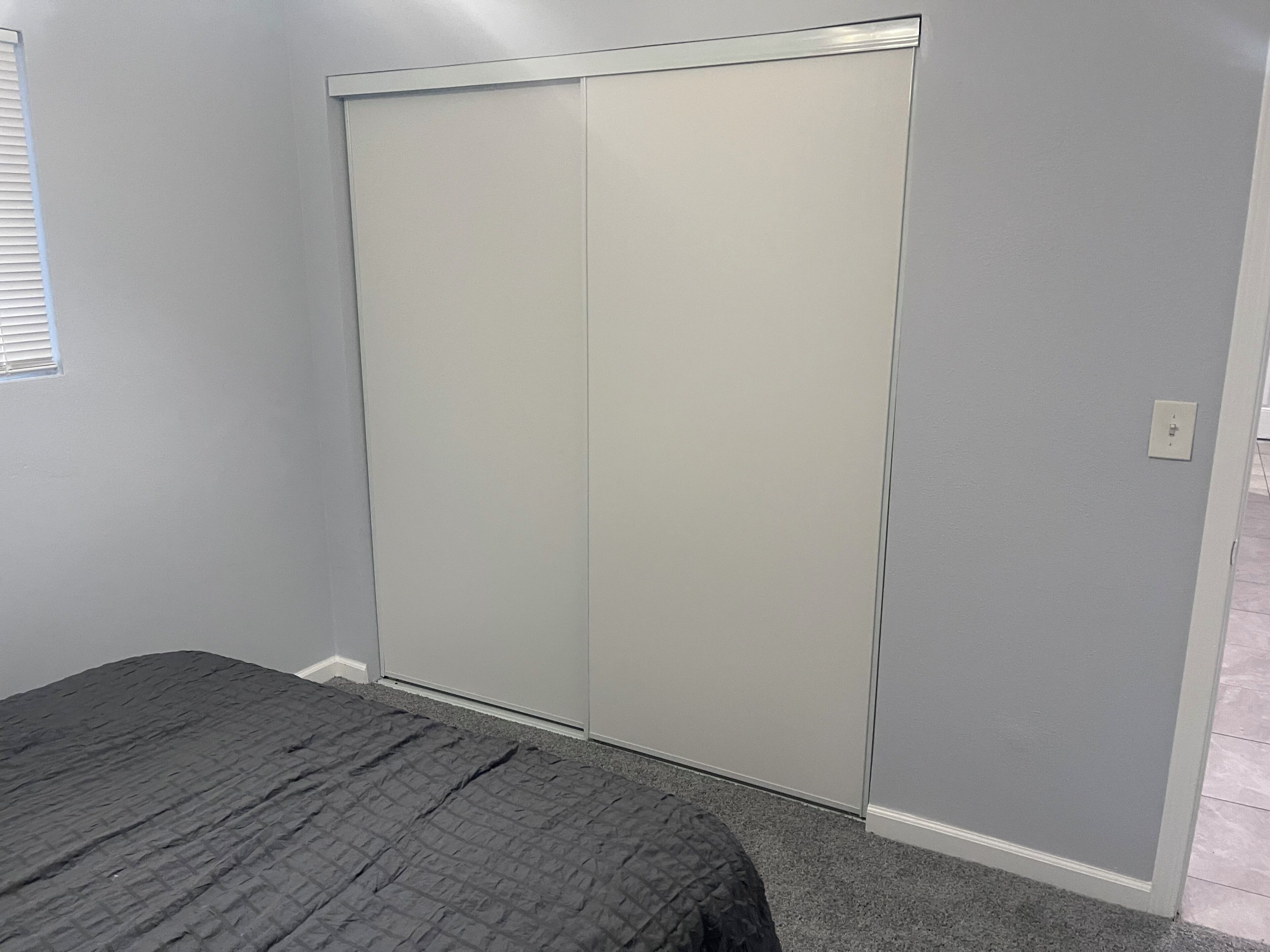 Une chambre avec un lit, une armoire et une prise de courant au mur.