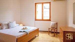 Une chambre à coucher avec un lit, une chaise, une commode et une fenêtre.