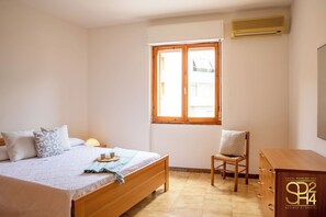 Ein Schlafzimmer mit einem Bett, einem Sessel, einem Schminktisch und einem Fenster.