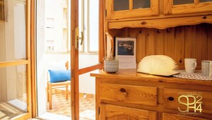 Un meuble en bois avec une porte en verre, un tableau encadré, un éventail décoratif et une tasse posée sur une table.