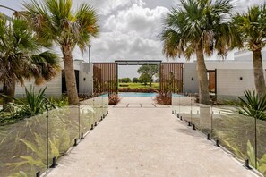 A pathway leading to a pool with palm trees and a modern building in the background. - Vista Cana private Jacuzzi + Golf + Beach + Pool (Punta Cana)