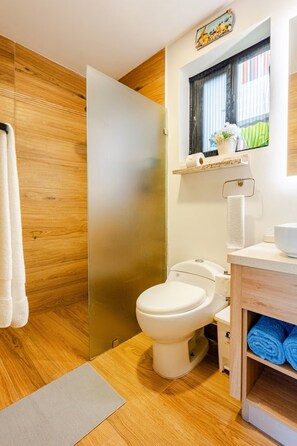 A bathroom with a wooden floor, a white toilet, a wooden vanity, a towel rack, and a window with blinds. - Vista Cana private Jacuzzi + Golf + Beach + Pool (Punta Cana)