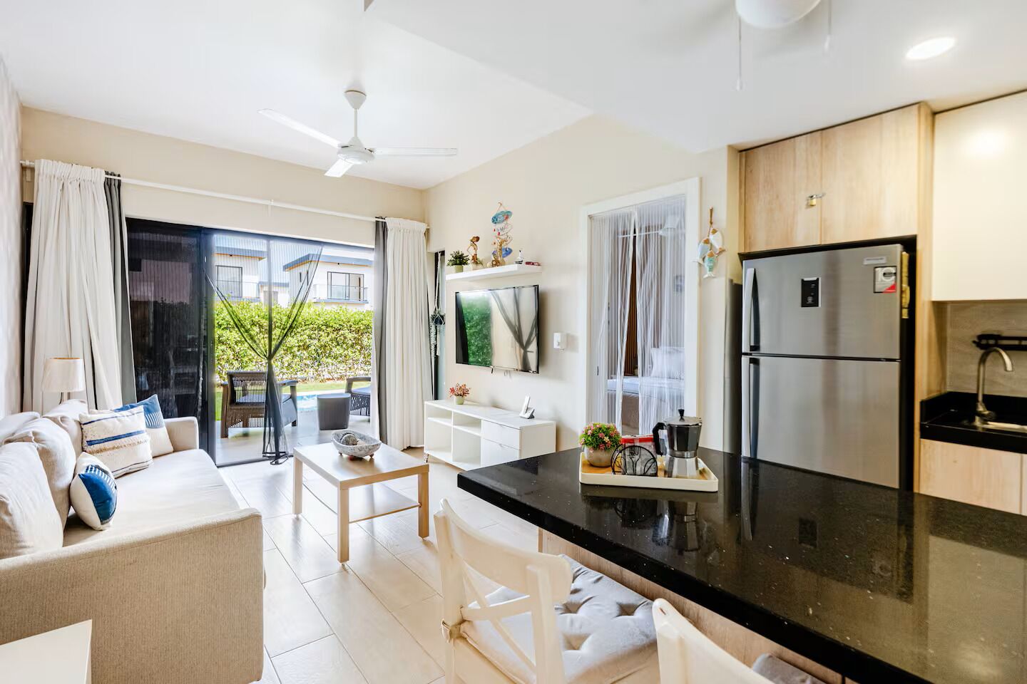 Een moderne keuken met een zwart aanrecht, roestvrijstalen apparatuur en een zithoek met een bank en tafel.