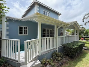 Ein zweigeschossiges Haus mit überdachter Veranda, einem Schwimmbad und einem gepflegten Garten.