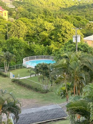A swimming pool surrounded by lush greenery, with a fence and a few buildings in the background. - Cap Estate 3BR Townhome, Private Plunge Pool, Golf (Gros Islet)