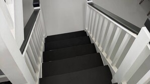 A staircase with white railings and black steps leading to a living area with a sofa and a glass coffee table. - Cap Estate 3BR Townhome, Private Plunge Pool, Golf (Gros Islet)