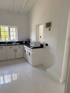 A kitchen with white cabinets, a black countertop, a microwave, and a window with a view of greenery. - Cap Estate 3BR Townhome, Private Plunge Pool, Golf (Gros Islet)