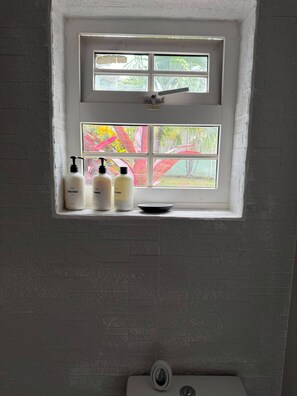 A bathroom with a window, a toilet, and three bottles of toiletries on the window sill. - Cap Estate 3BR Townhome, Private Plunge Pool, Golf (Gros Islet)