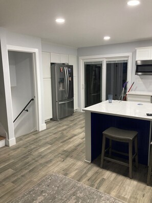 A modern kitchen with a stainless steel refrigerator, a built-in oven, and a bar area with stools. - 3-bedroom house in terrific Gastonia with cool AC breeze. (Gastonia)