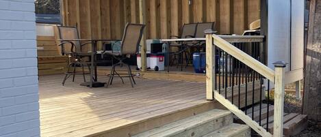 A wooden deck with outdoor furniture, a covered seating area, and a staircase leading to a deck.