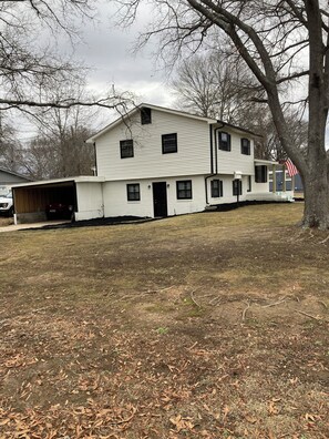 Une maison à deux étages avec un garage, une véranda et un drapeau américain.