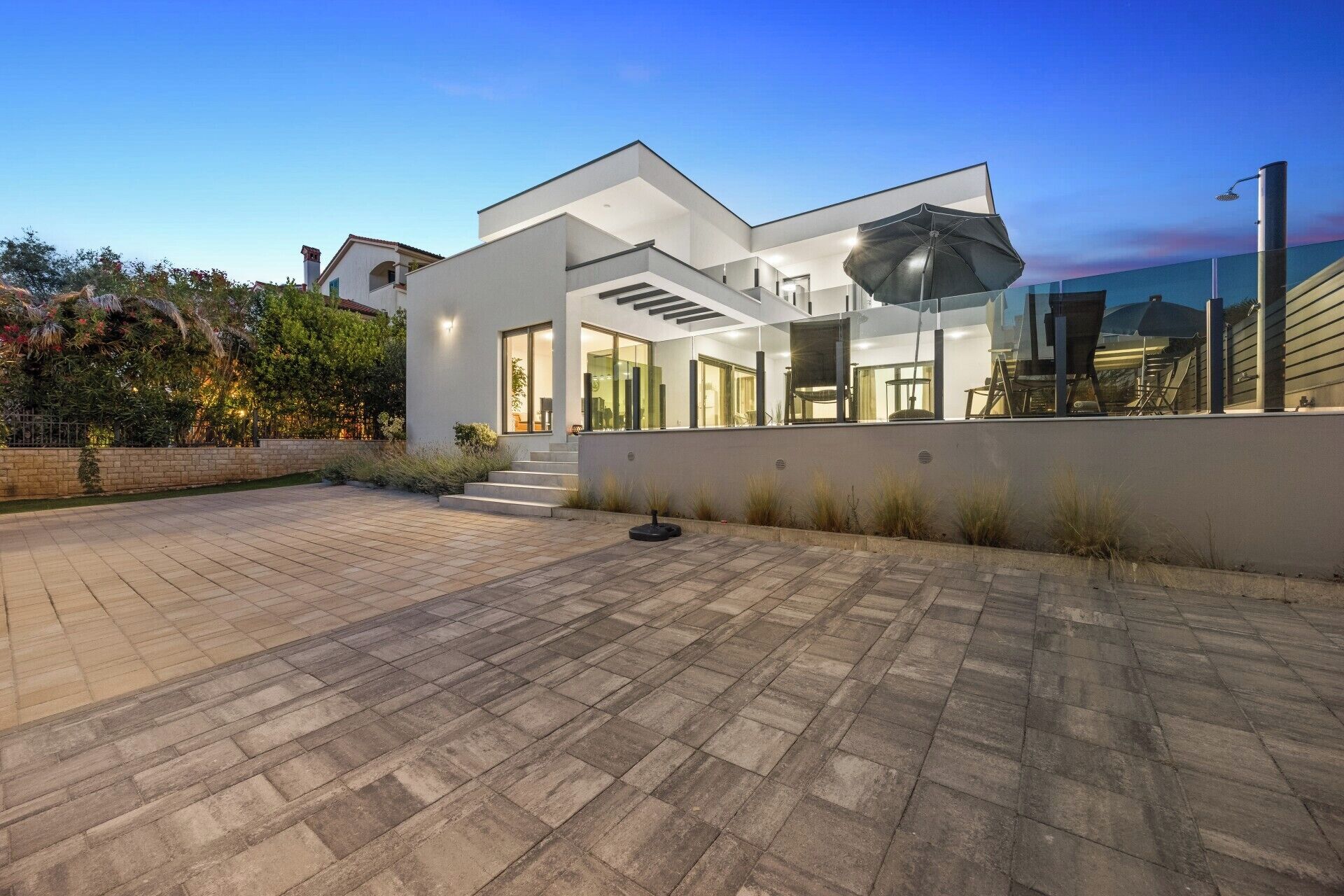 Une maison moderne dotée d’un vaste patio, de grandes fenêtres et d’un intérieur bien éclairé.