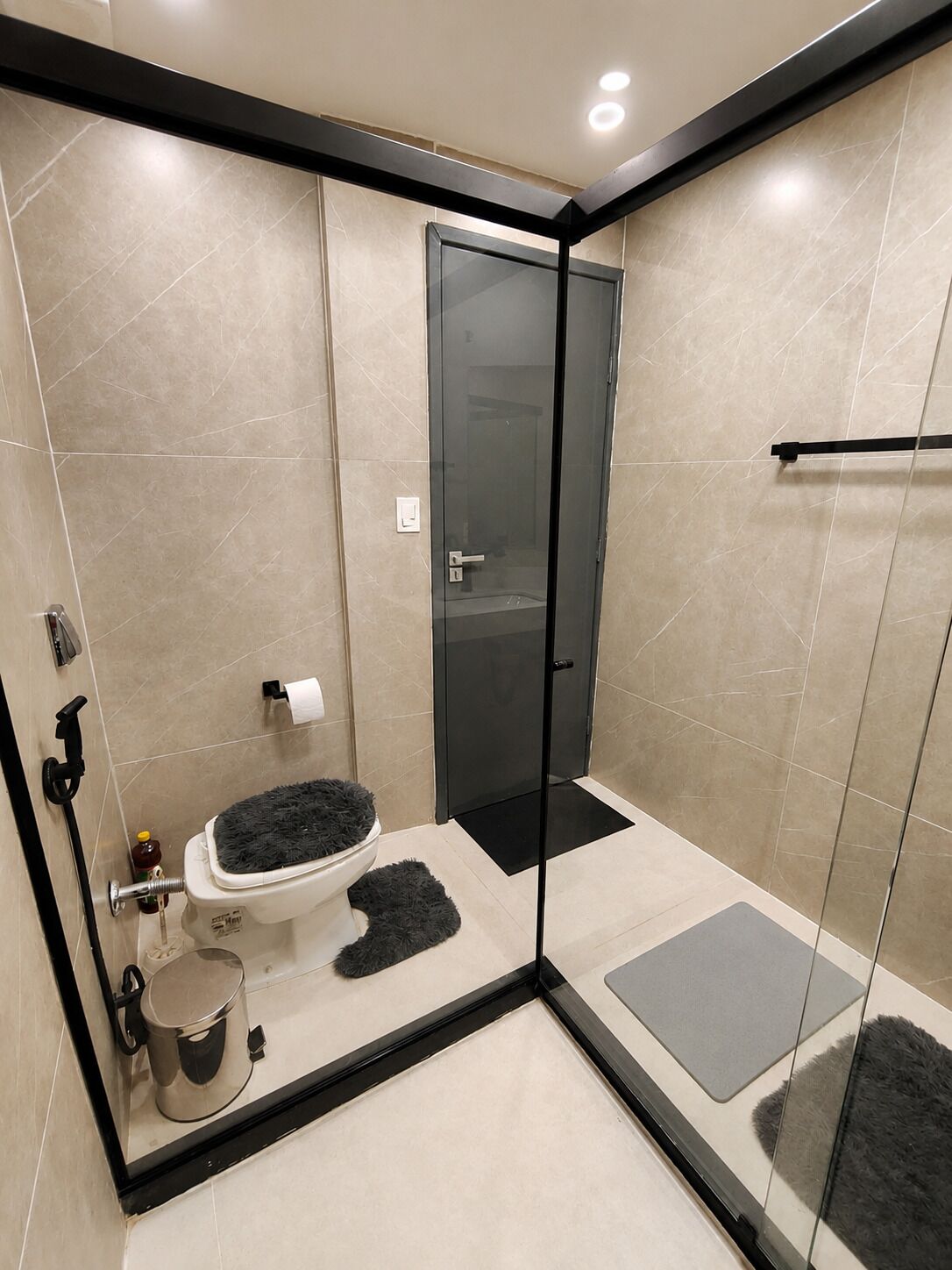 Ein modernes Badezimmer mit Duschkabine aus Glas, Toilette mit schwarzem Teppich und Bidet.