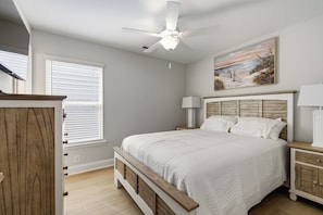 A bedroom with a bed, a nightstand, a dresser, a ceiling fan, and a painting on the wall. - Walkin' On Sunshine - Walk to Surfside Beach! (Surfside Beach)
