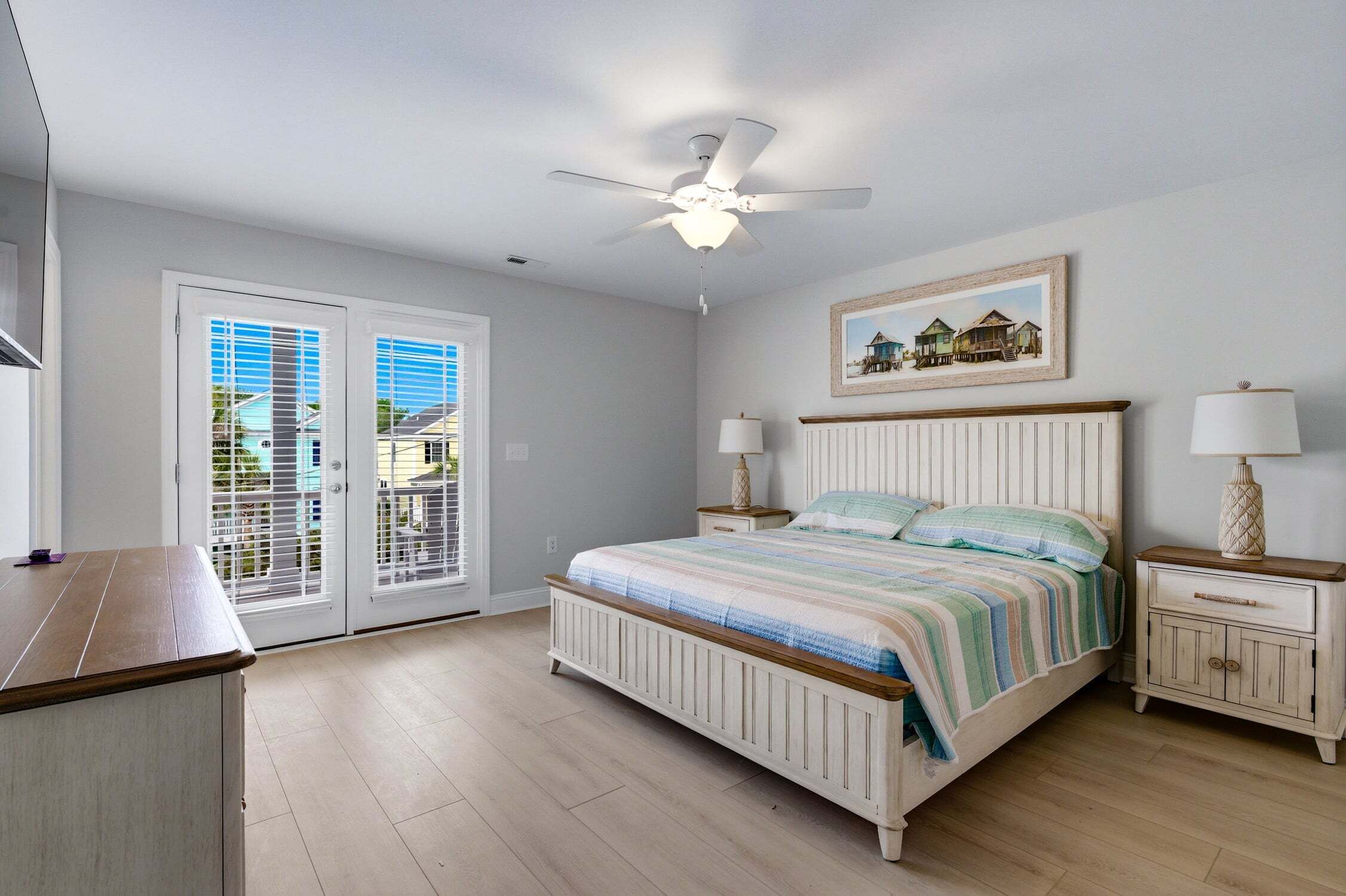 A bedroom with a bed, two bedside tables, a ceiling fan, and a window with blinds.