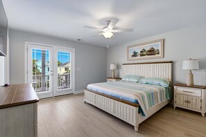 Quarto com uma cama, duas mesas de cabeceira, um ventilador de teto e uma janela com persianas.