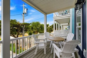 A covered porch with white railings, a round wooden table, and white chairs. - Walkin' On Sunshine - Walk to Surfside Beach! (Surfside Beach)