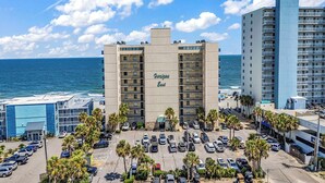 Ein Hotel mit Meerblick, einem Parkplatz und einem Strand im Hintergrund.