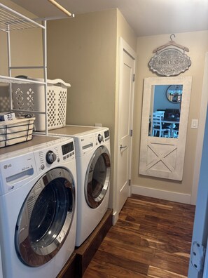 A laundry room with two LG front-loading washers, a drying rack, and a self-service laundry sign. - Gorgeous Jewel of West Side Rapid City, in the heart of where you want to be! (Rapid City)