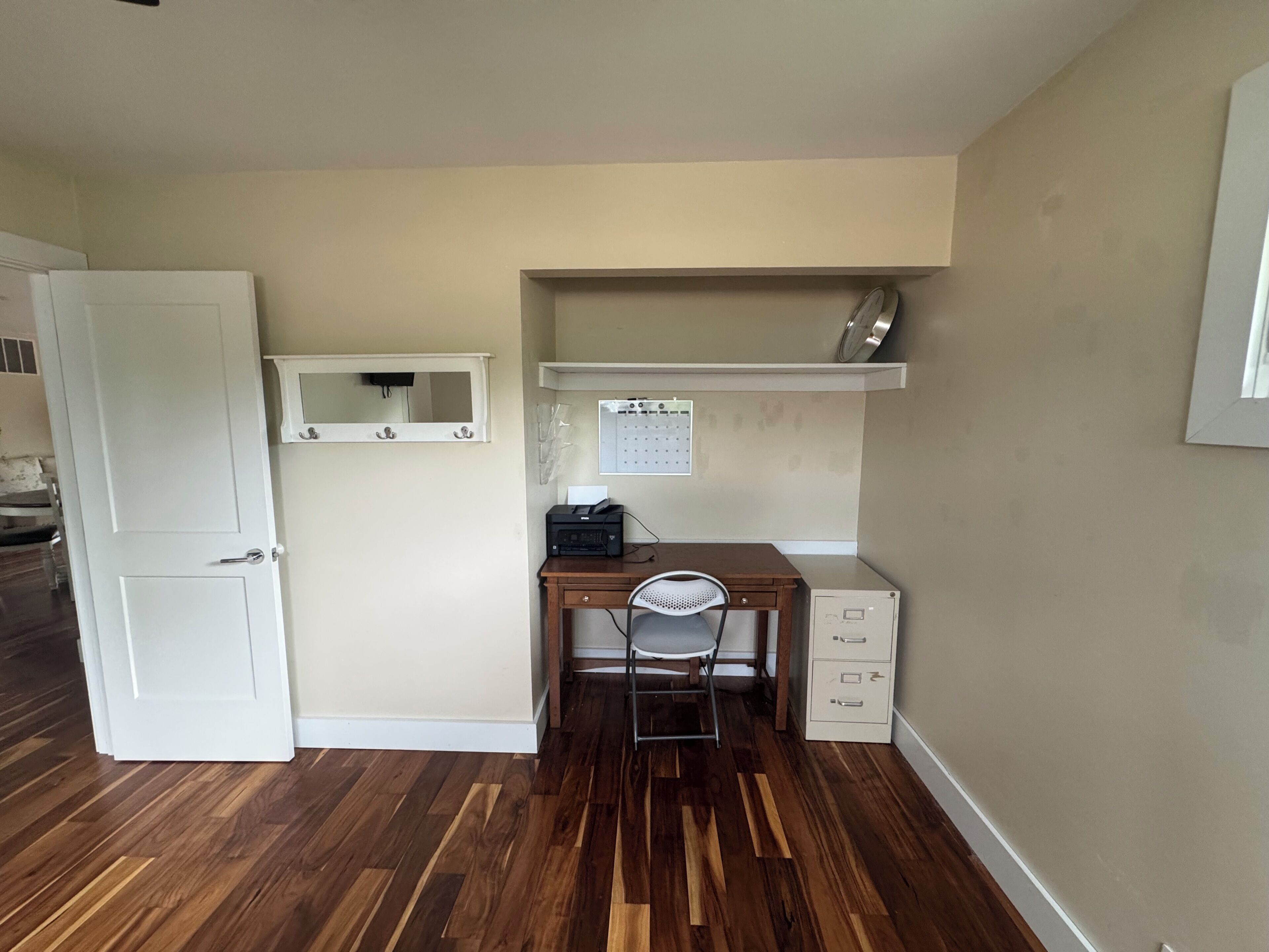 A small office space with a desk, chair, filing cabinet, and a white door.