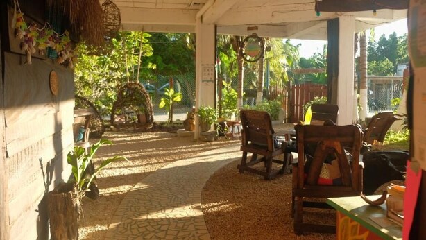 An indoor area with a tiled floor, wooden furniture, and a thatched roof. - Hostal & Camping El Árbol de la Vida. (Bacalar)