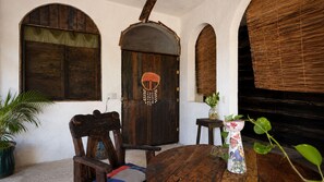 A rustic interior with a wooden door, a round wooden table, and a chair. - Hostal & Camping El Árbol de la Vida. (Bacalar)