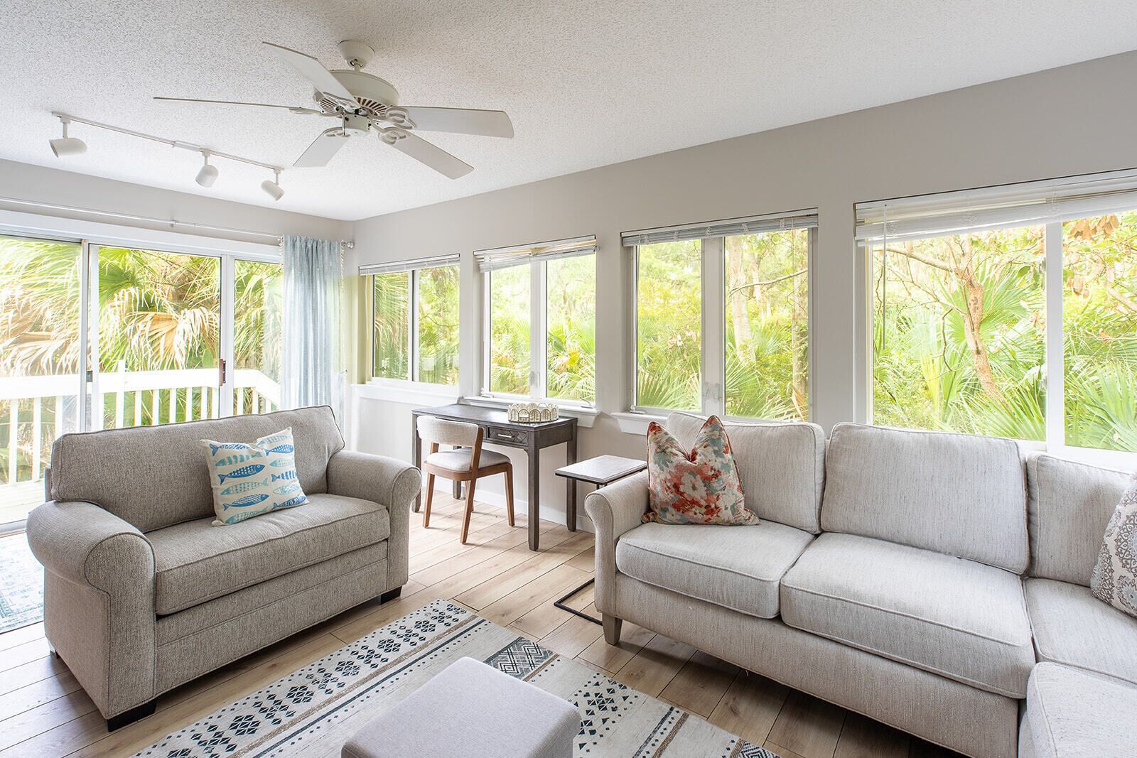 A spacious living area with two sofas, a dining table, and a ceiling fan.