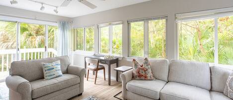 A spacious living area with two sofas, a dining table, and a ceiling fan.