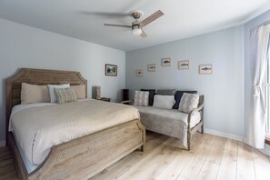 Ein Schlafzimmer mit einem großen Bett, einem kleineren Bett, einem Deckenventilator und gerahmten Bildern an der Wand.