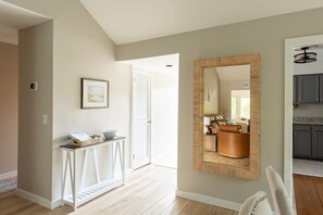 A hallway with a white console table, a framed picture, and a mirror on the wall. - Double Bogey by Sandpiper | Near Beach (Seabrook Island)
