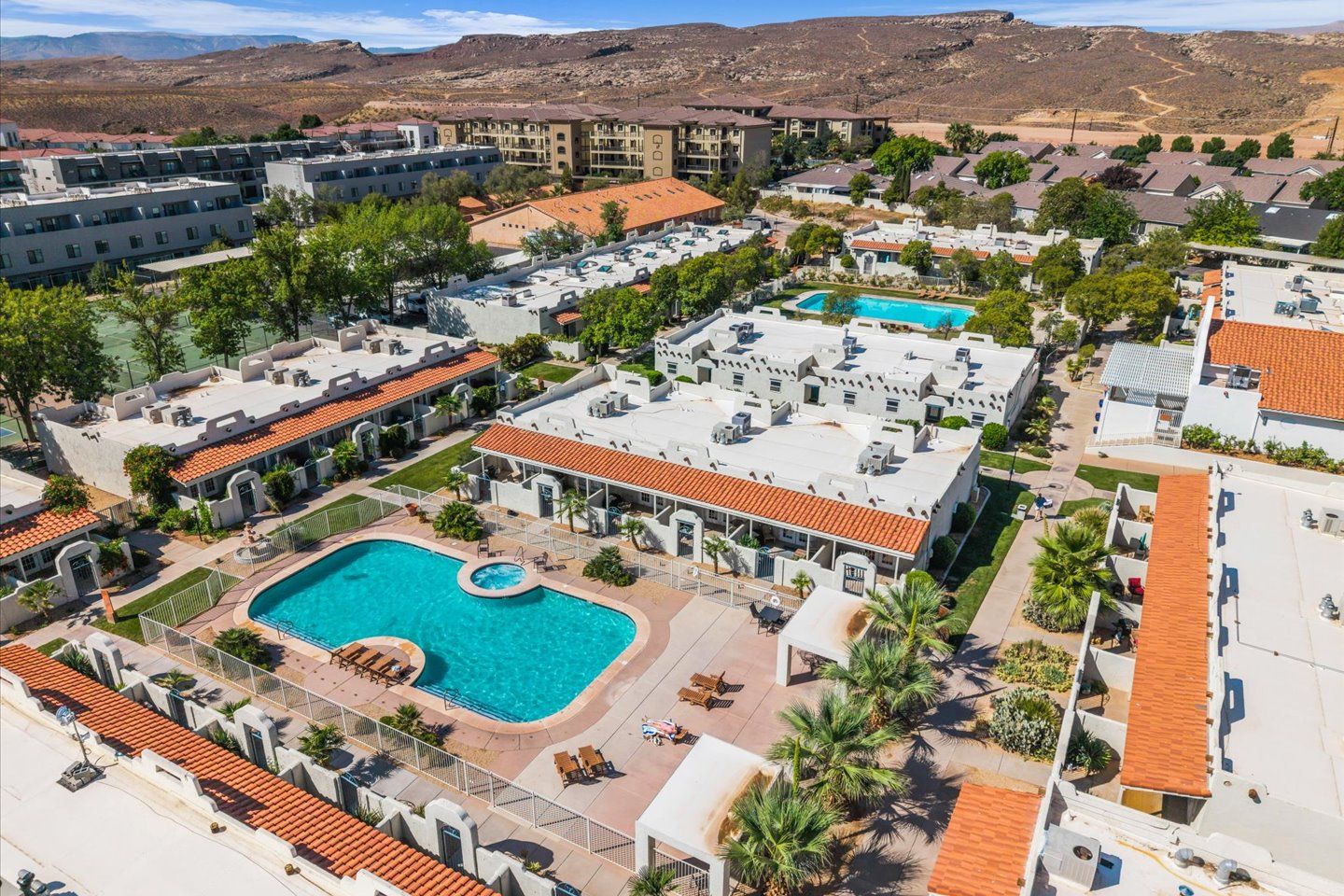 Un resort con diversi edifici, una piscina centrale e montagne sullo sfondo.