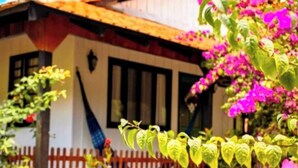 Una casa con techo rojo, paredes blancas y cerca de madera.