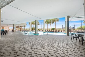 An outdoor swimming pool area with lounge chairs and a covered seating area.