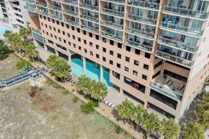 Un hôtel à plusieurs étages doté de balcons, d’une piscine et d’un espace paysager agrémenté d’arbres.