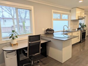 A modern kitchen with a central island, a built-in sink, and a stove. - The Bloom House - 2 Bedroom 2 Bath Family Home (Vancouver)