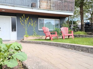 A residential building with a front porch, two red Adirondack chairs, and a small garden with yellow flowers. - The Bloom House - 2 Bedroom 2 Bath Family Home (Vancouver)