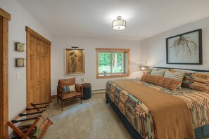 Ein Schlafzimmer mit Bett, Stuhl, Fenster und einem Bild an der Wand.