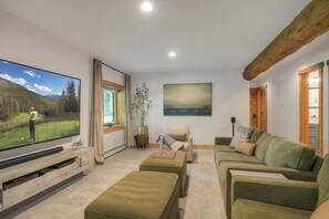 A living room with a flat-screen TV, a sofa, a chair, and a coffee table. - Mountain Chic Cabin | Hot Tub, Firepit & Seclusion in Blue River (Blue River)