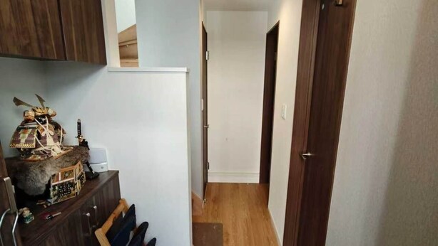 A hallway with a wooden floor, a shoe rack, and a door on the right. - Sakura Villa (Sumida City)