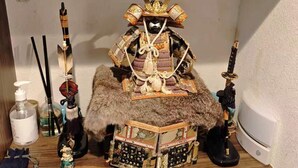A wooden table with a samurai statue, a fur-covered stool, and various personal items. - Sakura Villa (Sumida City)