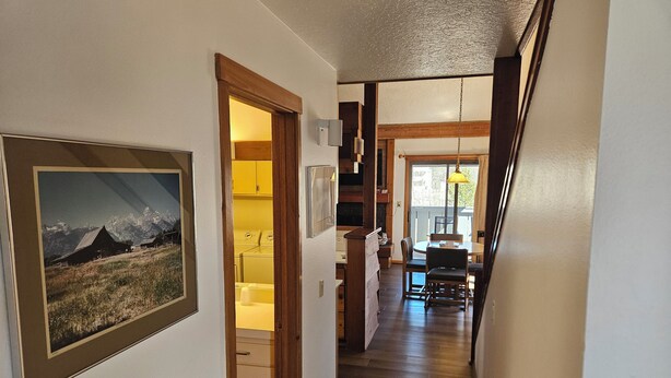 Un couloir orné d’un tableau encadré, un espace dédié à la buanderie et un coin repas avec une table et des chaises.