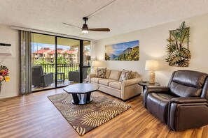 A living room with a sofa, a coffee table, a leather chair, a floor lamp, and a painting on the wall. - South Kihei Luxury Condo • Gorgeous Sunset Views. Steps to Kamaole Beach III (Kihei)