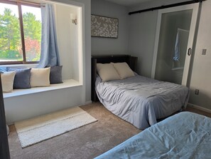 A bedroom with a bed, a window seat with cushions, a carpeted floor, and a door. - 5 min to Penn State, Airport. King Bed, Game Room, Breakfast. Family Friendly! (State College)