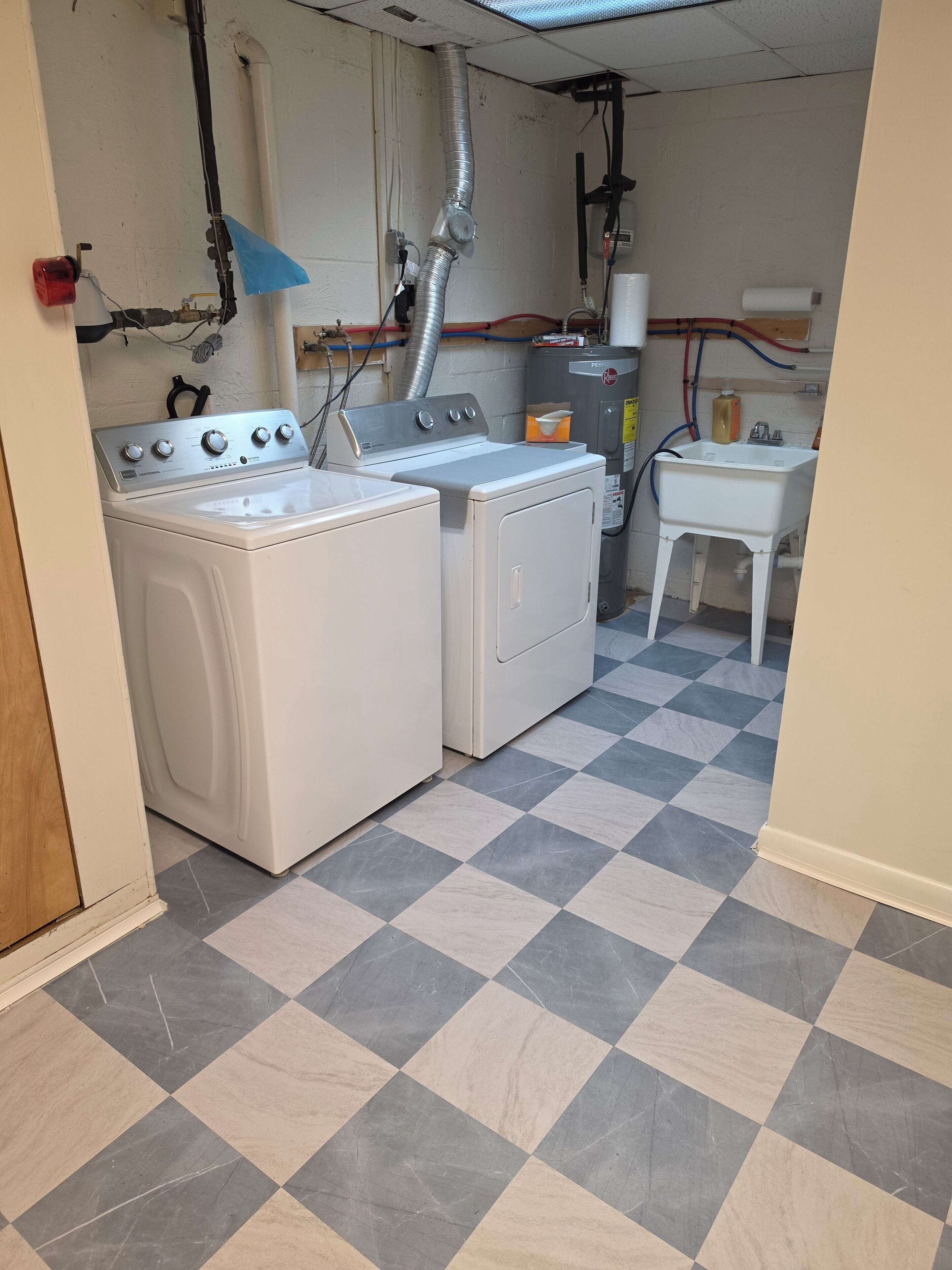 Un cuarto de lavandería con dos lavadoras, un lavabo y un calentador.