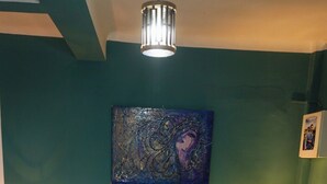 Ein Schlafzimmer mit einem Bett, zwei Nachttischlampen, einem Nachttisch, einer Bank, einem Bild an der Wand und einer Deckenleuchte.