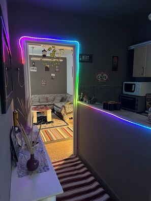 A narrow hallway with a bed, a sofa, and a kitchen area with a microwave. - Comfortable Apartment in the Heart of Tunis – Explore the City Easily (Tunis)