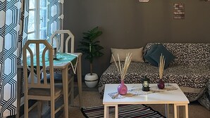 Ein Wohnzimmer mit einer Couch, einem Tisch, Stühlen, einem Deckenventilator und Wanddekorationen.